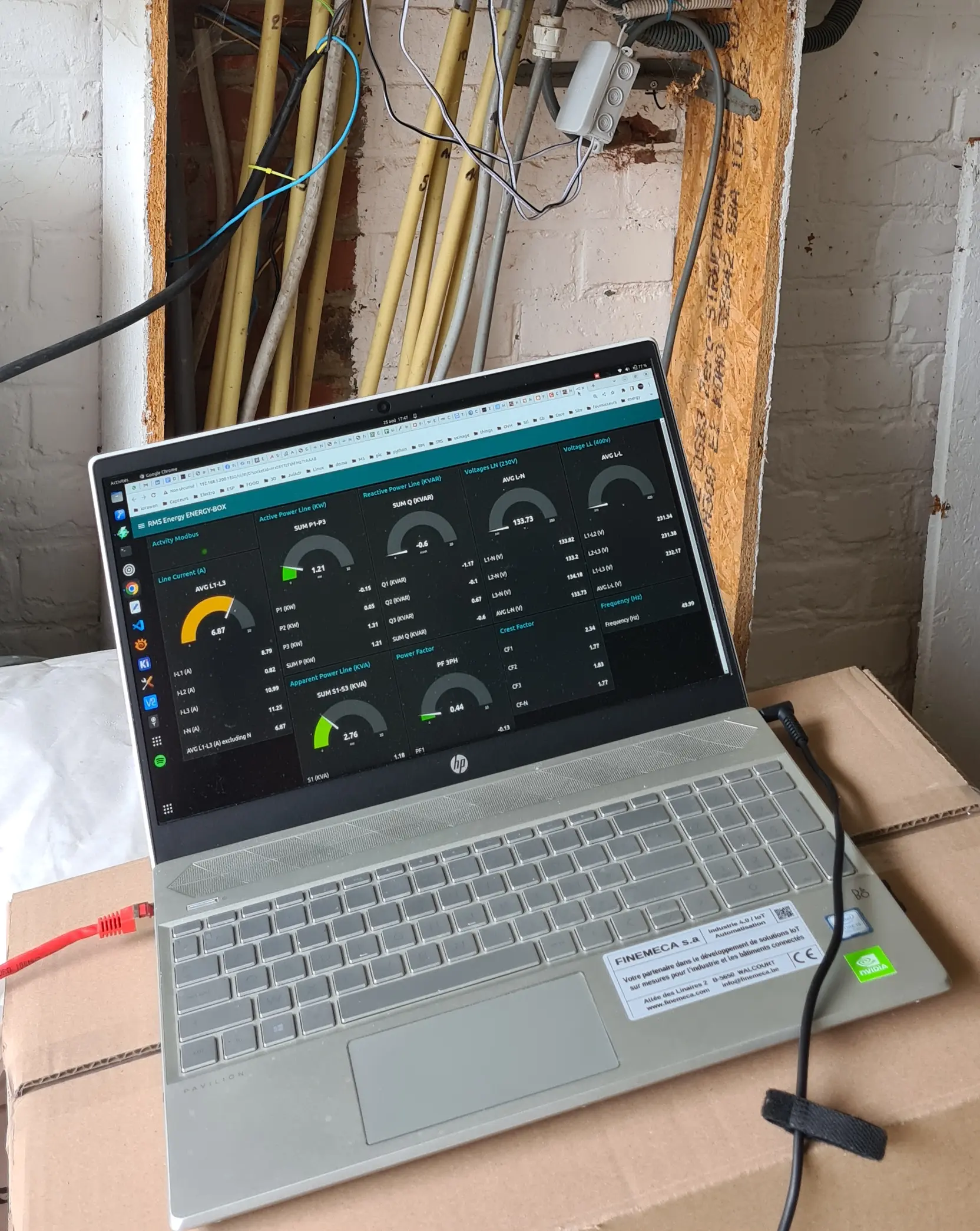 Ordinateur portable affichant les mesures d'une Energy-Box en cours de campagne, devant une saignée de câbles