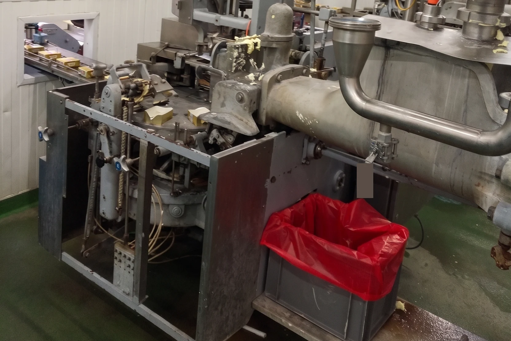 Machine de conditionnement ancienne, carters ouverts, tôles corrodées et résidus de produit accumulés sur le mécanisme