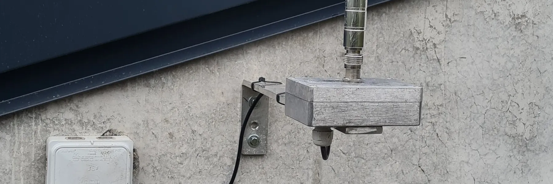 Gateway LoRaWAN d'extérieur équipée d'une antenne fibre, fixée sur le mur béton d'un bâtiment industriel